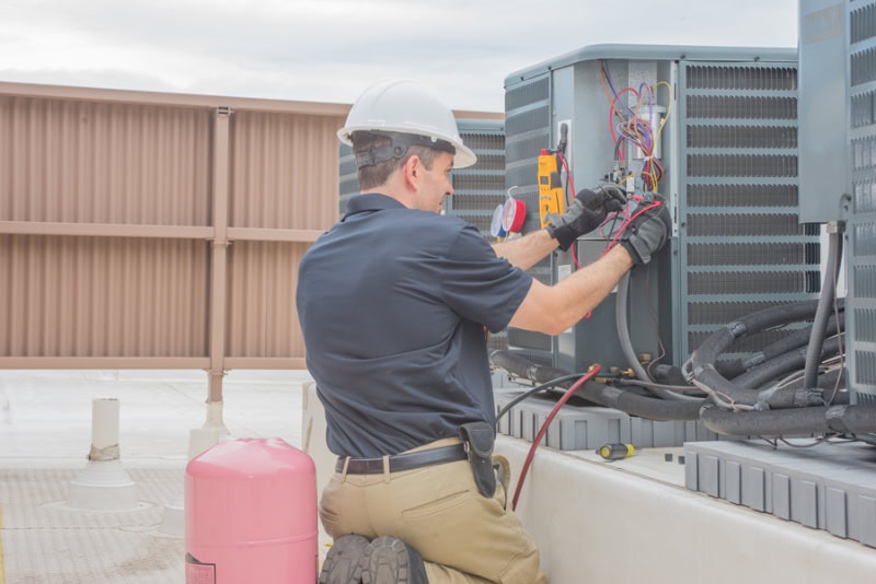 Technician checking for power on a rooftop condensing unit.