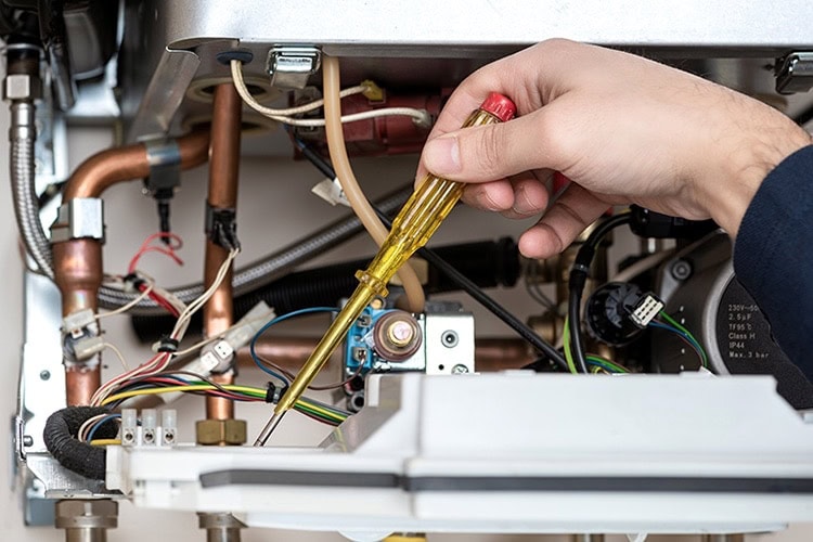 man fixing a furnace unit with a screwdriver