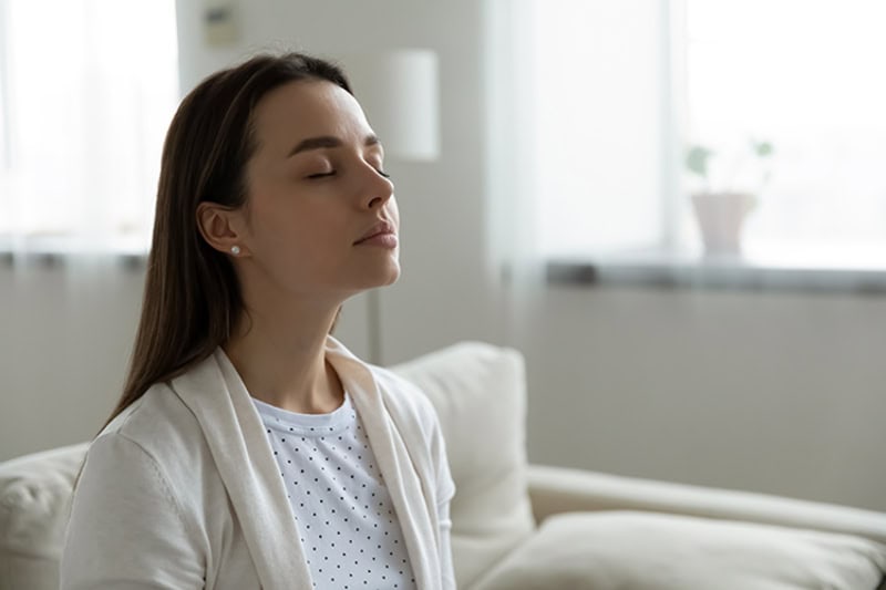 Woman taking deep breath on couch.