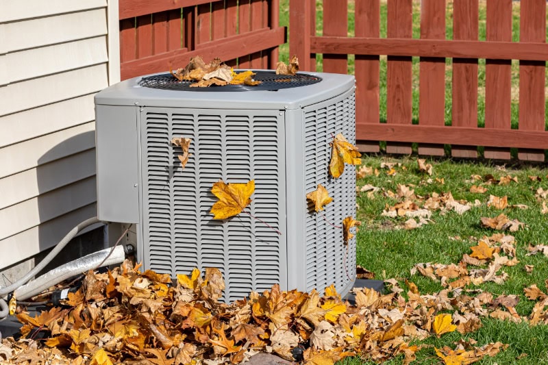 Fall HVAC Maintenance. Dirty air conditioning unit covered in leaves during autumn. Home air conditioning, HVAC, repair, service, fall cleaning and maintenance.